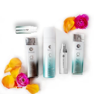 Se muestran cinco botellas en el set Integral de Cuidado de La Piel que incluye: Age IQ Crema para Noche, Iluminador y protector IllumaBoost, Suero para Ojos Age IQ, Limpiador de Doble Acción Age IQ y Age IQ Crema para Día de Neora. 